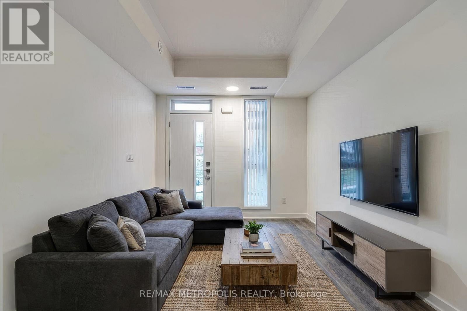 A living room with a grey couch, a wooden coffee table, and a flat screen TV mounted on the wall.