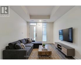 A living room with a grey couch, a wooden coffee table, and a flat screen TV mounted on the wall.
