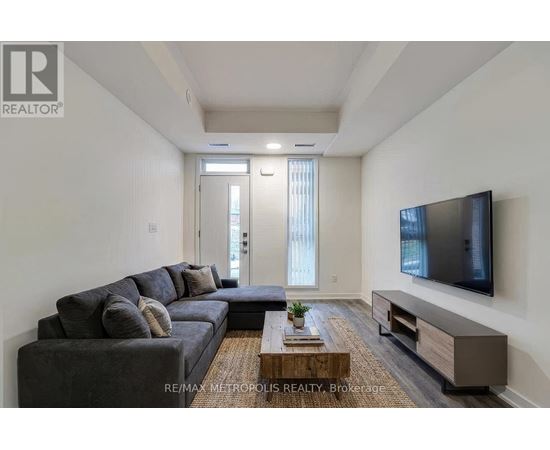 A living room with a grey couch, a wooden coffee table, and a flat screen TV mounted on the wall.
