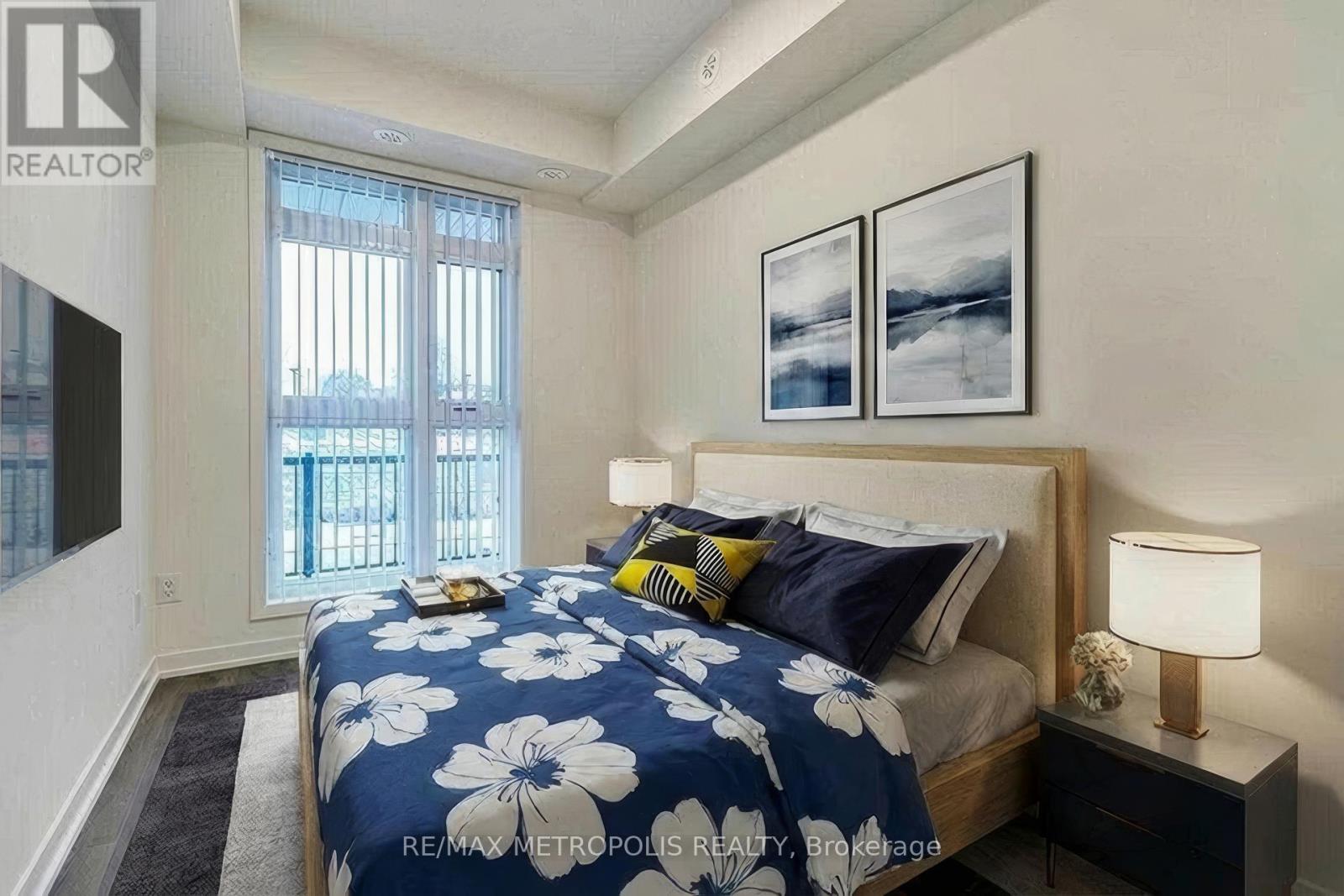 A bedroom with a bed, nightstand, and two pictures on the wall.
