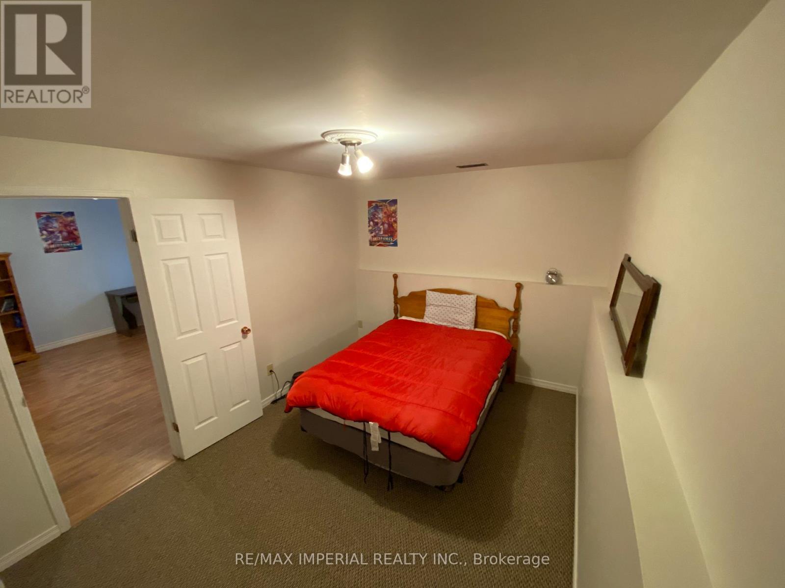 A bedroom with a red bed and a white door.