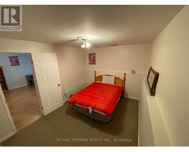 A bedroom with a red bed and a white door.