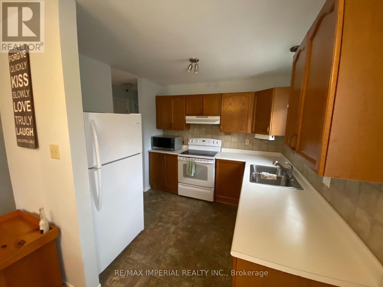 A kitchen with a white refrigerator, wooden cabinets, and a white countertop.