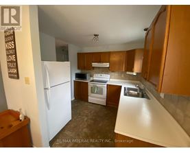 A kitchen with a white refrigerator, wooden cabinets, and a white countertop.