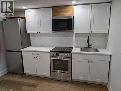A kitchen with white cabinets and a wooden backsplash.