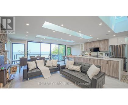 A modern living room with a grey sofa set and a kitchen area with stainless steel appliances.