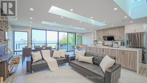 A modern living room with a grey sofa set and a kitchen area with stainless steel appliances.