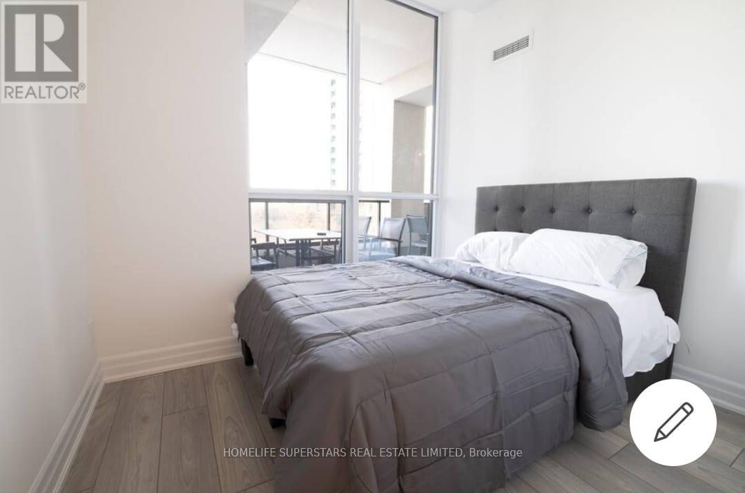 A bedroom with a large bed and a window overlooking a balcony.