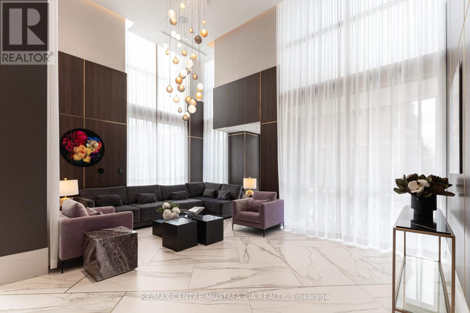 A living room with a brown and white color scheme and a chandelier hanging from the ceiling.