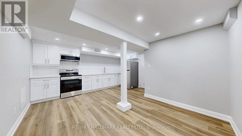 A spacious kitchen with white cabinets and a wooden floor.