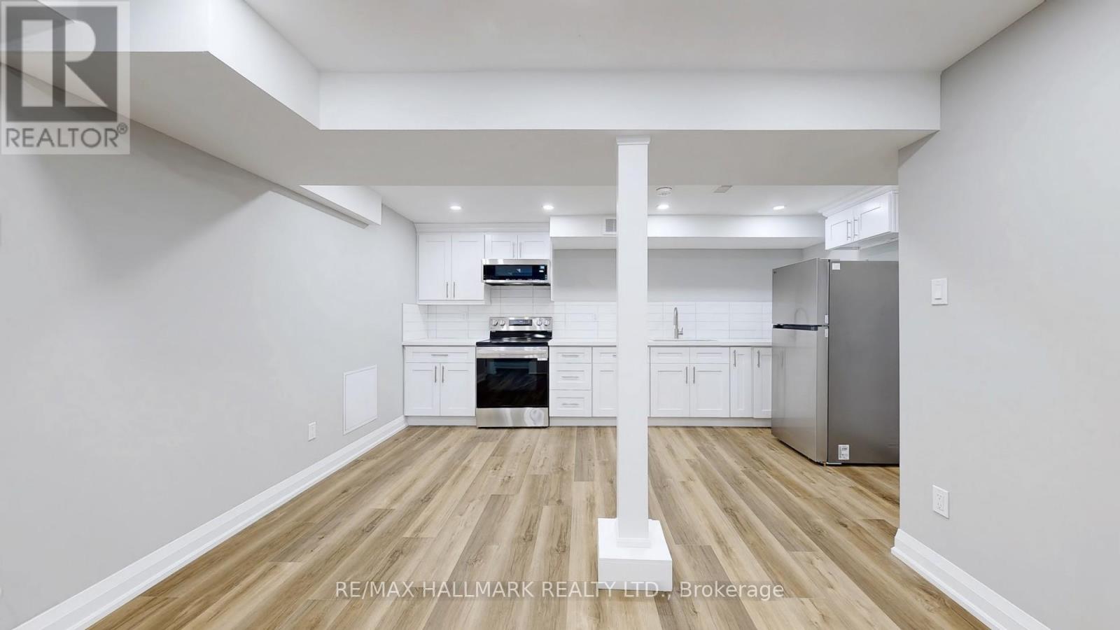 A spacious kitchen with white cabinets and a wooden floor.