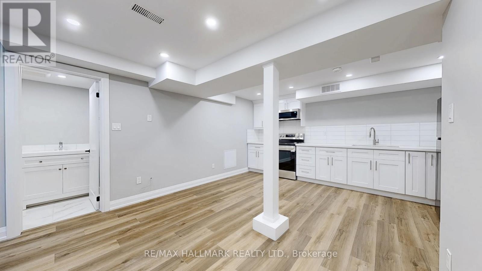A spacious kitchen with white cabinets and a wooden floor.