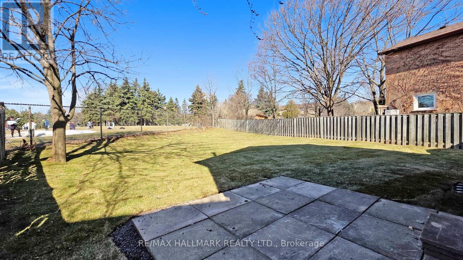 A backyard with a wooden fence and a brick building in the background.