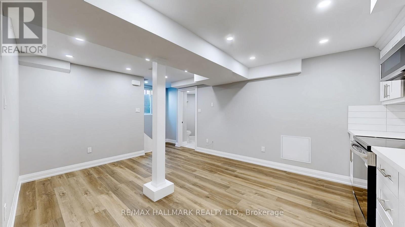 A spacious room with wooden flooring and white walls.