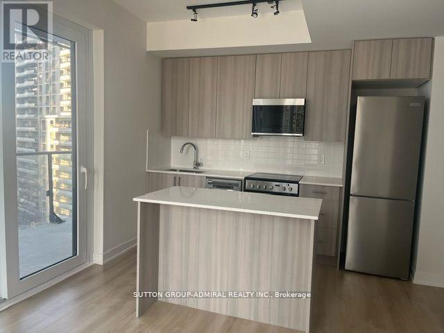 A kitchen with a refrigerator, microwave, and stove top oven.