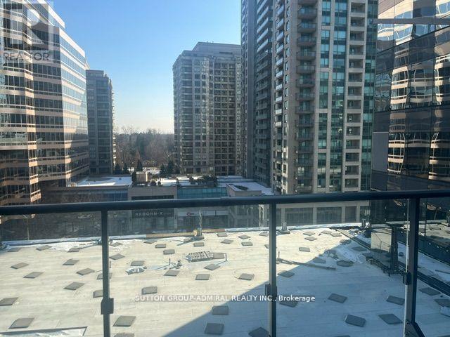 A view from a balcony overlooking a cityscape with buildings and a snow-covered ground.