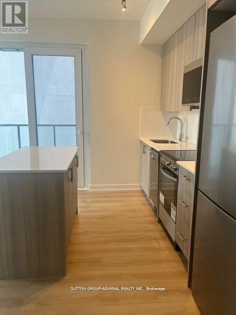 A kitchen with a refrigerator, sink, and stove.