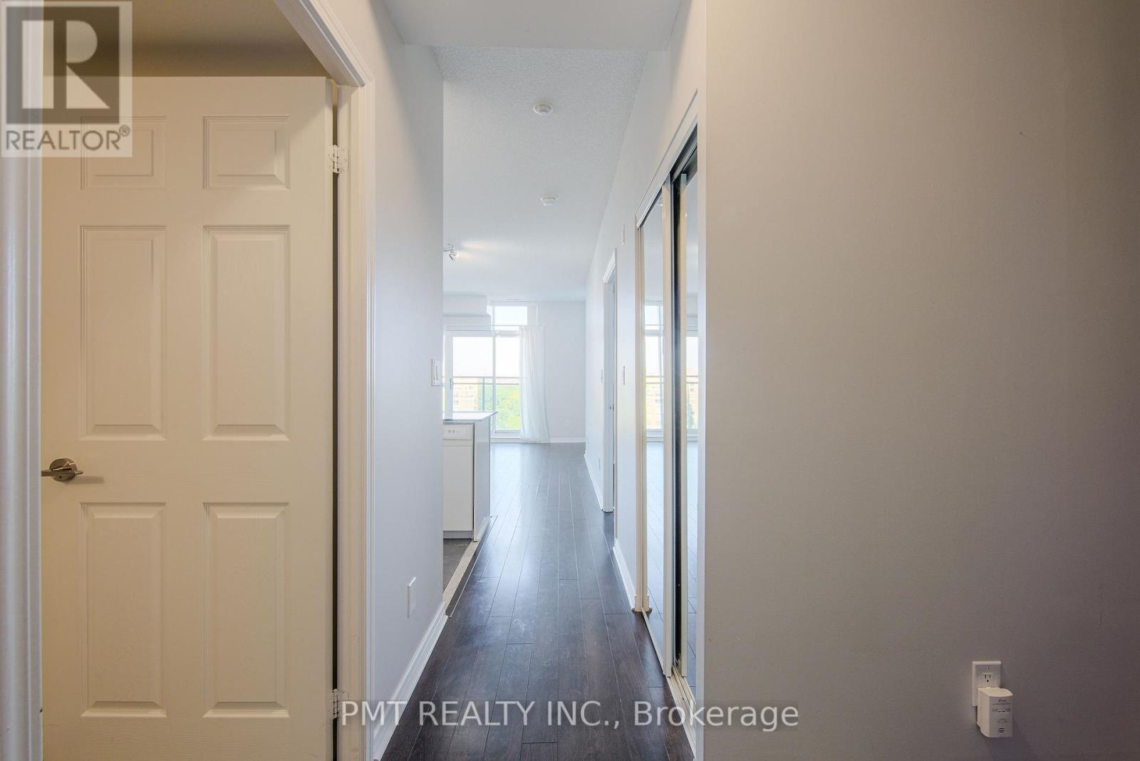 A hallway with a white door and a window in the distance.