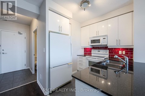 A kitchen with white cabinets and a white refrigerator.