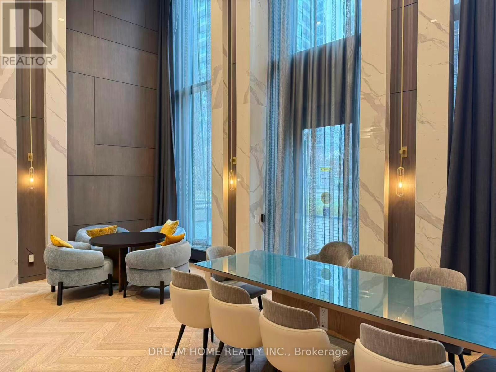 A modern dining room with a glass table and grey chairs.