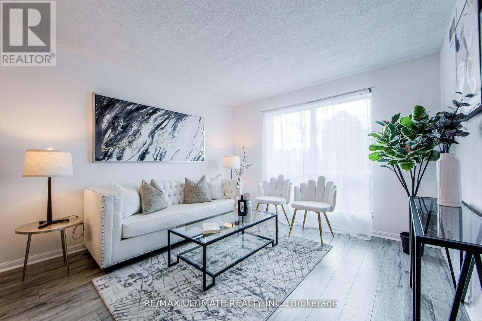 A living room with a white couch, a black coffee table, and a large abstract painting on the wall.