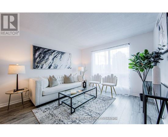 A living room with a white couch, a black coffee table, and a large abstract painting on the wall.