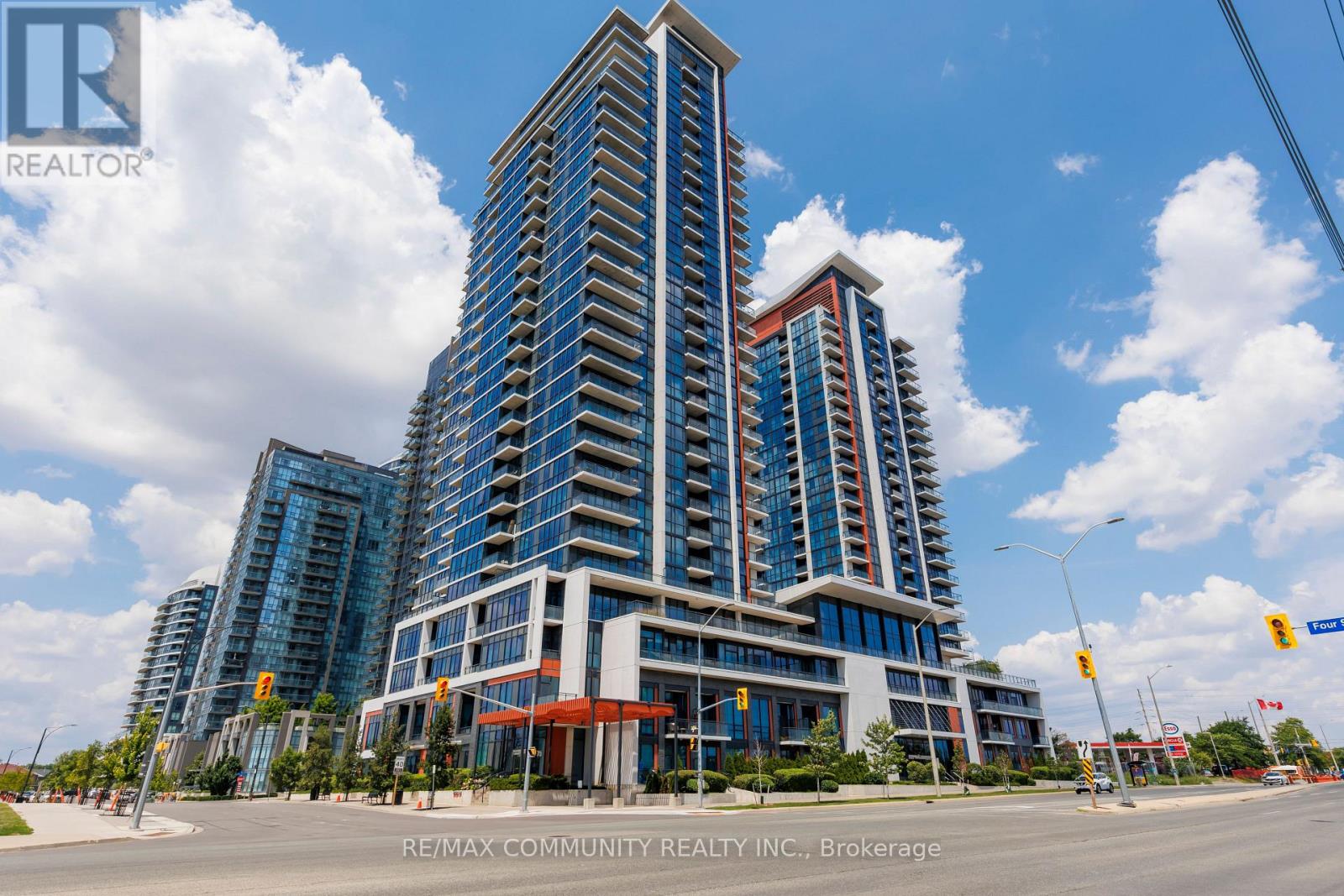 A modern multi-story building with a glass facade stands under a clear blue sky.