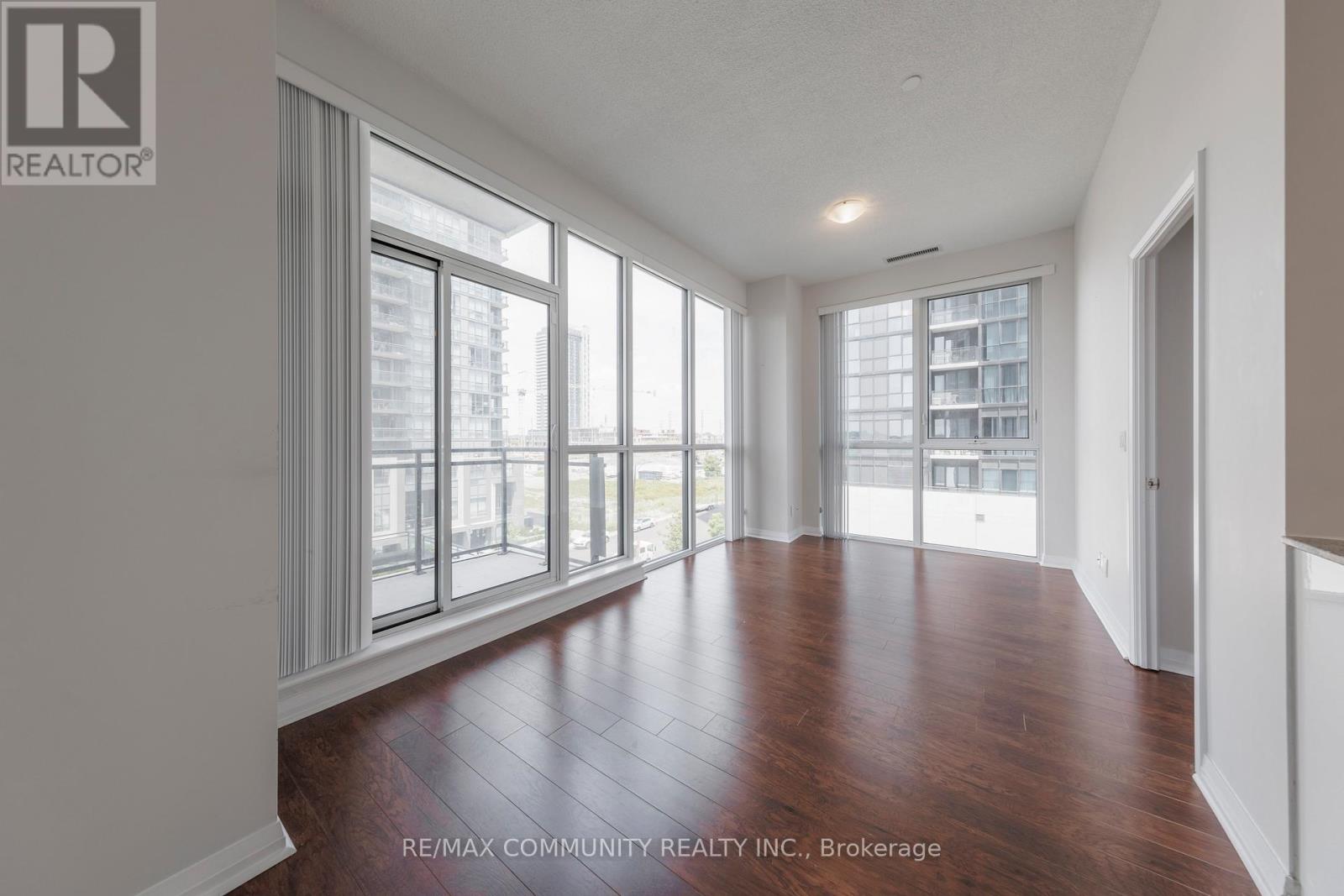 A spacious room with wooden floors and large windows.