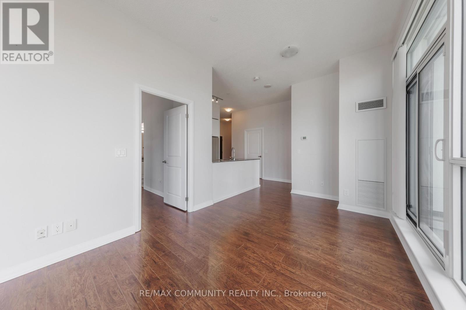 A spacious room with wooden flooring and white walls.