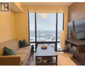 A living room with a couch, a coffee table, and a large window overlooking a cityscape.
