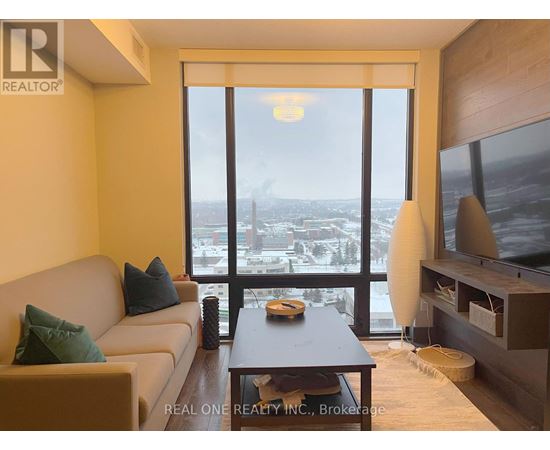 A living room with a couch, a coffee table, and a large window overlooking a cityscape.