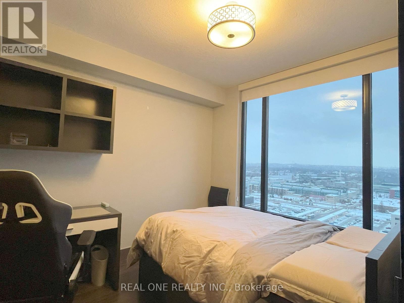A bedroom with a large bed and a desk with a chair.