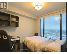 A bedroom with a large bed and a desk with a chair.