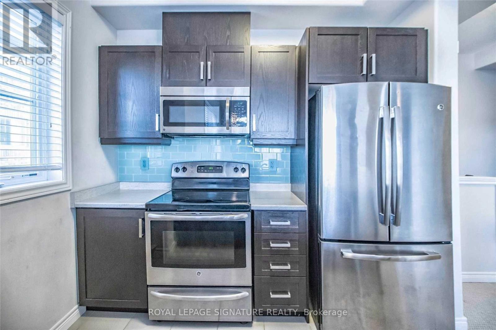 A kitchen with a stainless steel refrigerator, oven, and microwave.