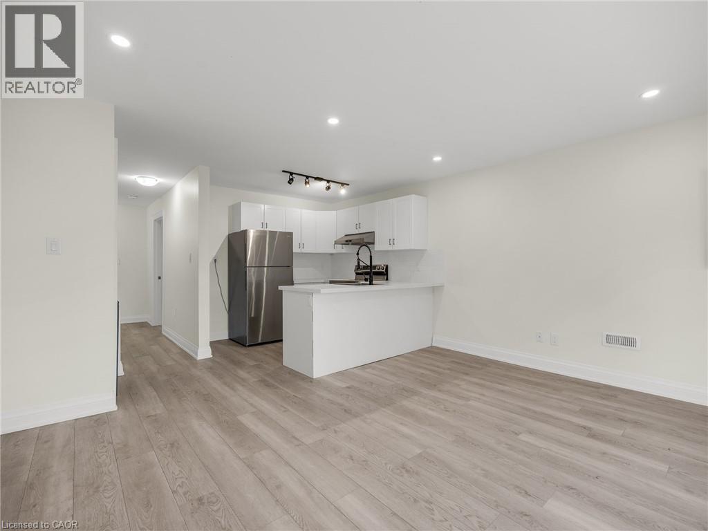 A spacious kitchen with white cabinets and a wooden floor.