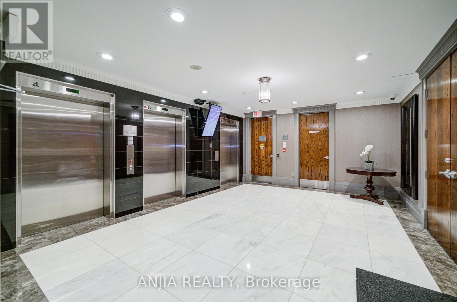 A spacious lobby with marble flooring and a mix of wood and glass doors.