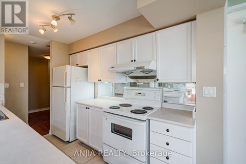 A white kitchen with a refrigerator, oven, and microwave.