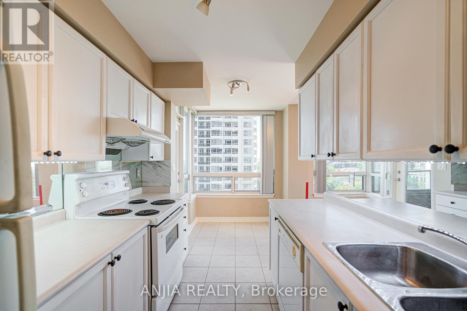 A kitchen with white appliances and beige cabinets.