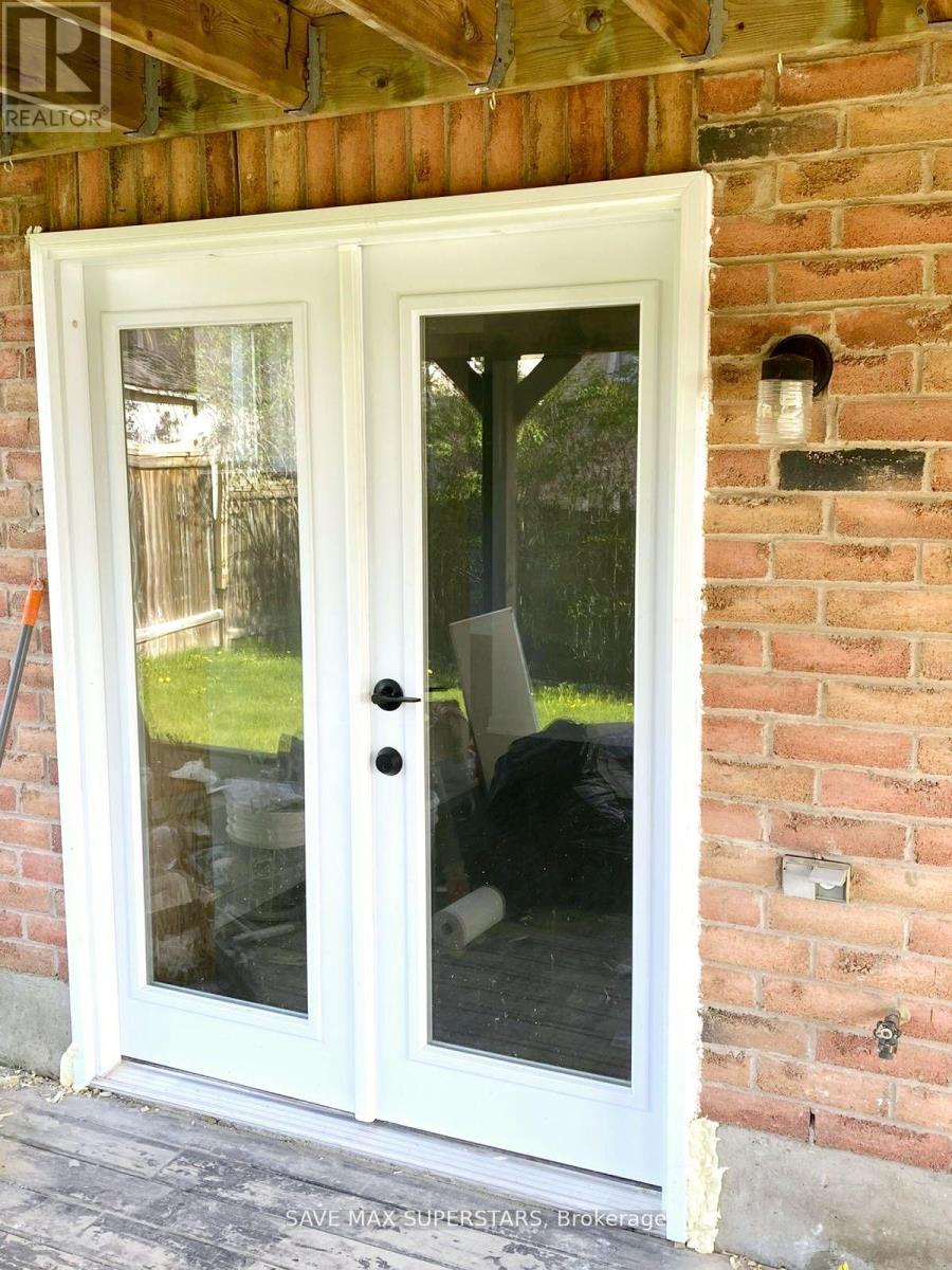 A white double door with a glass window is installed in a brick wall.