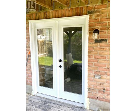 A white double door with a glass window is installed in a brick wall.