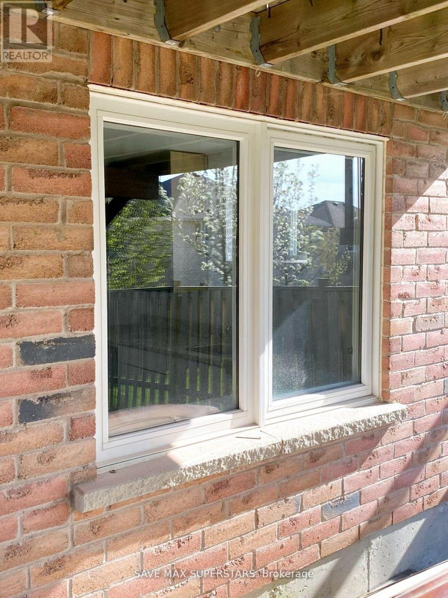 A window on a brick wall with a view of a fence and trees.