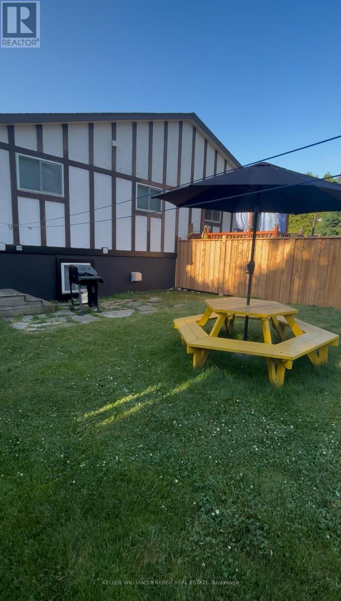 A yellow picnic table is in the middle of a grassy yard.