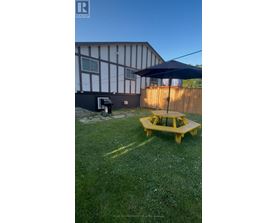 A yellow picnic table is in the middle of a grassy yard.