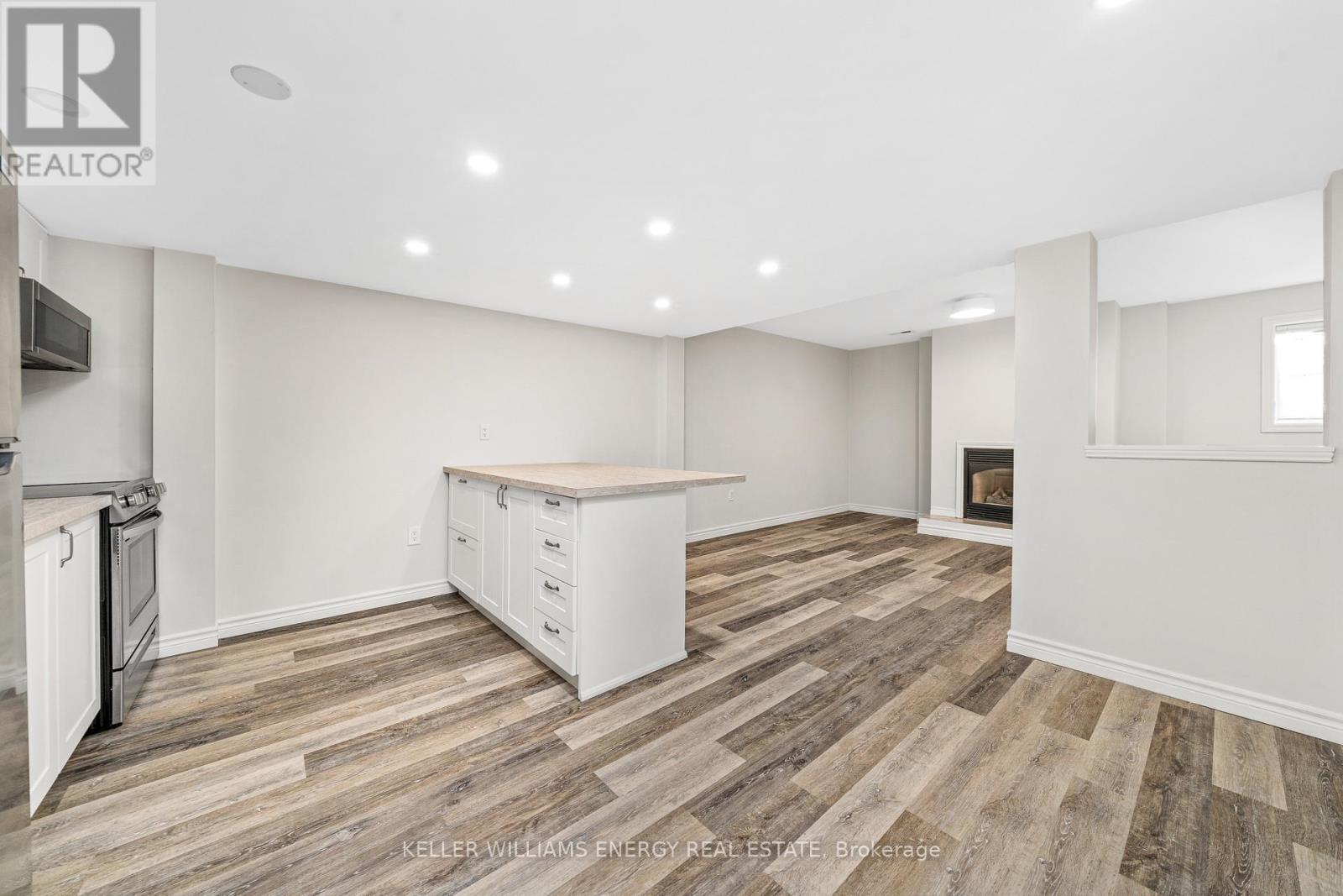 A spacious kitchen with white cabinets and a wooden floor.