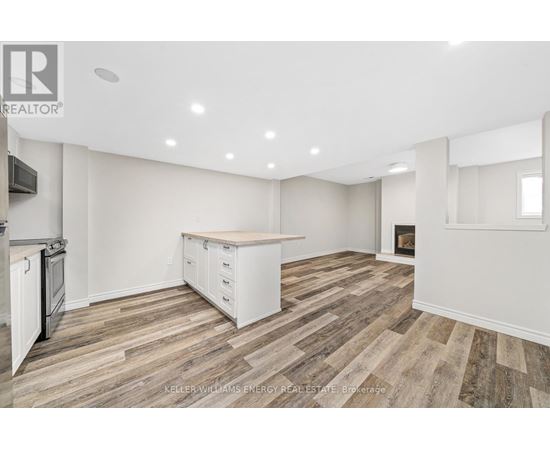 A spacious kitchen with white cabinets and a wooden floor.