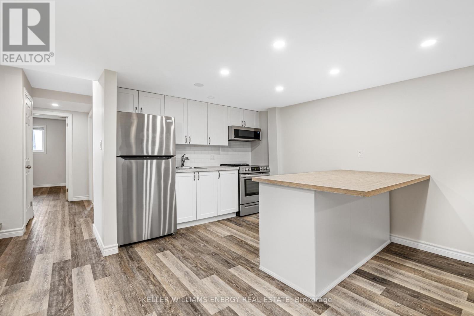 A kitchen with a white refrigerator, stove, and oven, and a wooden island in the middle.
