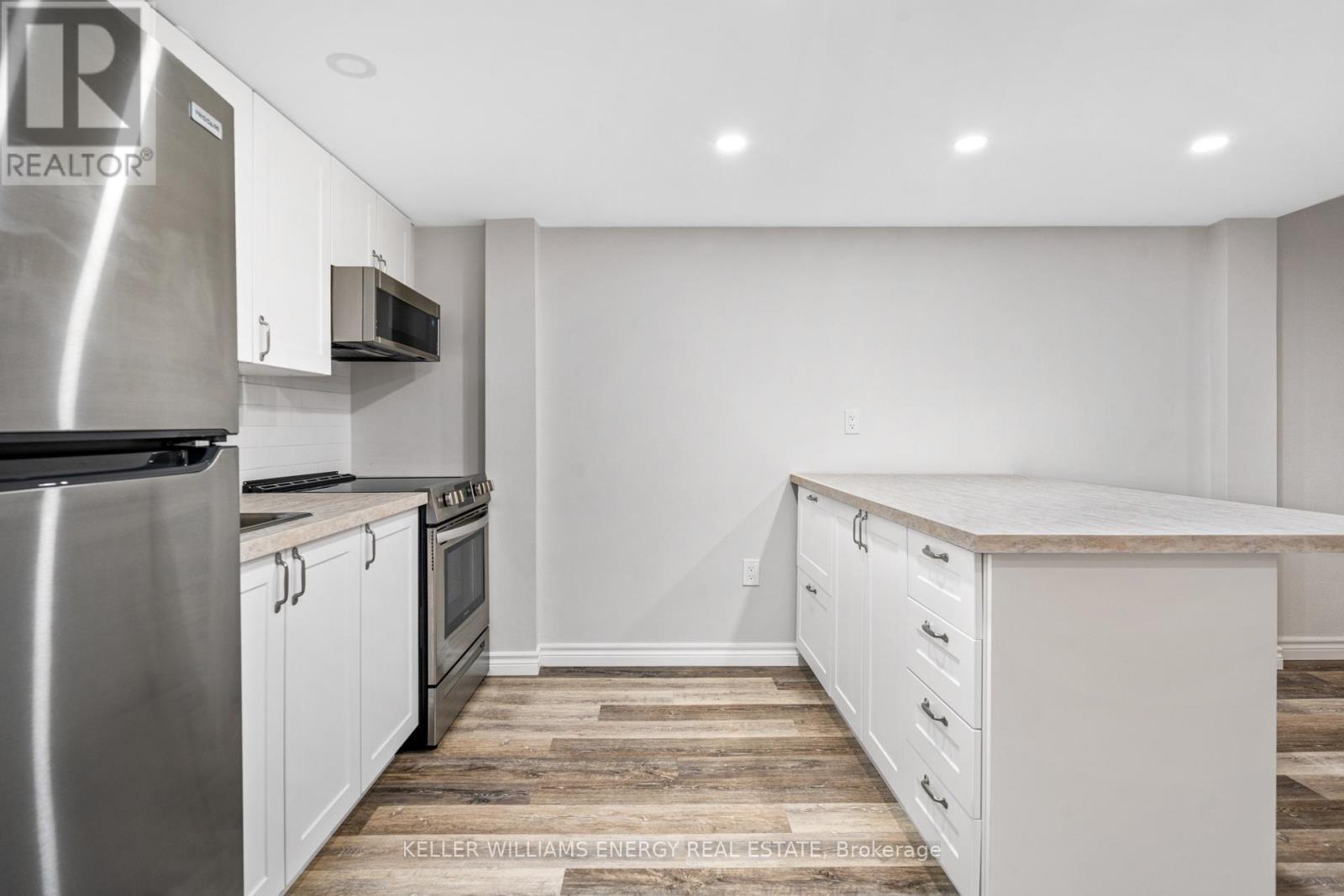 A kitchen with white cabinets and a stainless steel refrigerator.