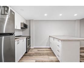 A kitchen with white cabinets and a stainless steel refrigerator.