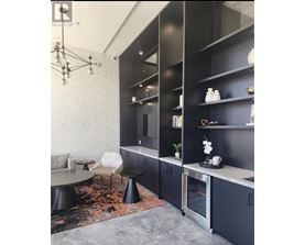 A modern kitchen with black cabinets and a grey floor.