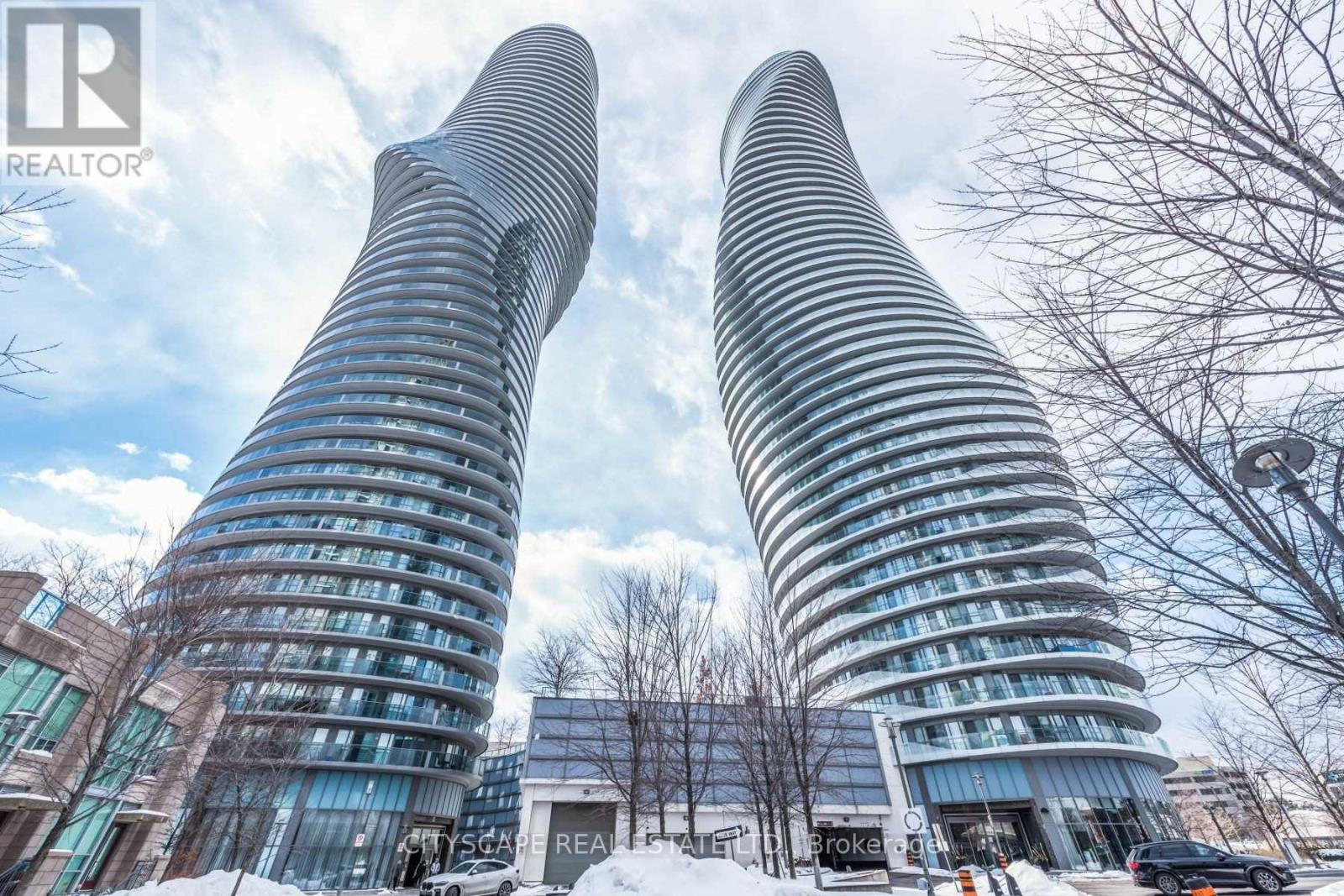 Two tall buildings with curved glass facades stand side by side.